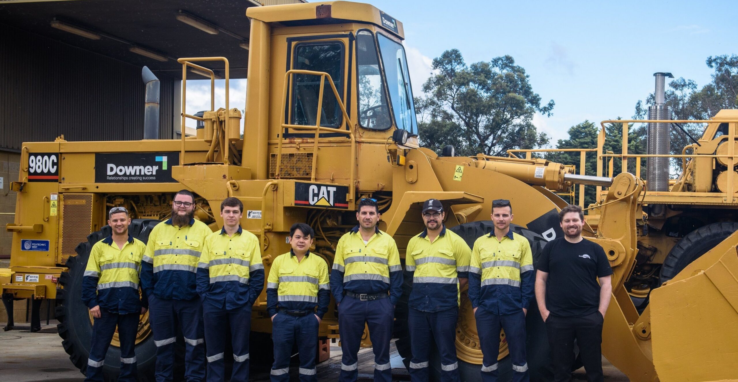 Blue Tongue apprentices standing with a wheel loader